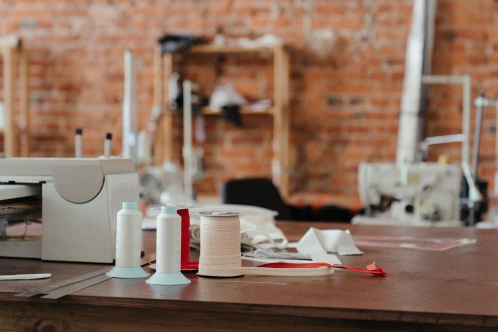 A sewing table featuring spools of thread and a sewing machine in a cozy workspace.